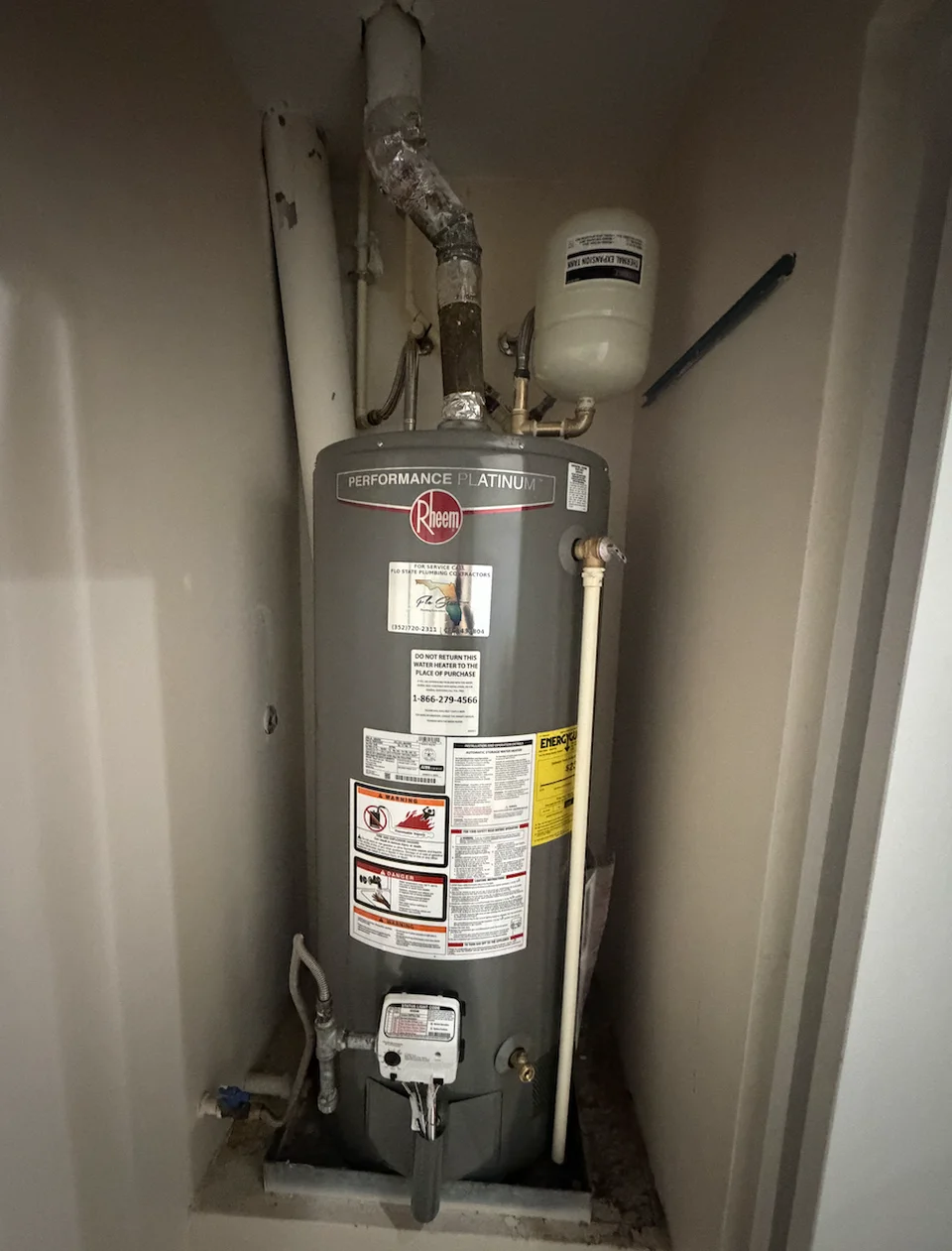 A Rheem Performance Platinum natural gas tank water heater installed in a closet with overhead venting and an expansion tank.
