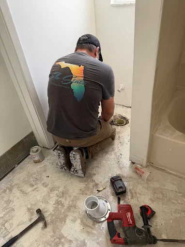 Plumber setting a closet flange on a bathroom subfloor