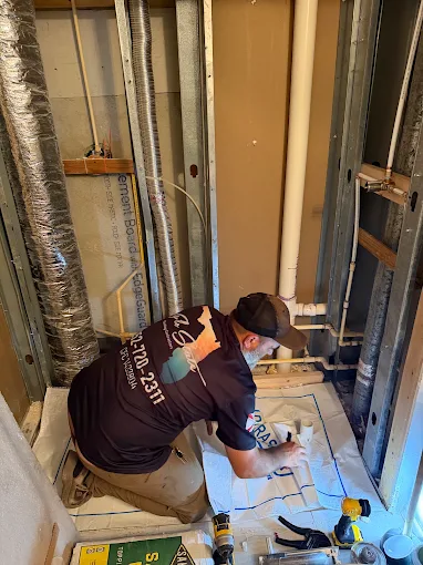 Plumber running new supply lines inside a framed wall