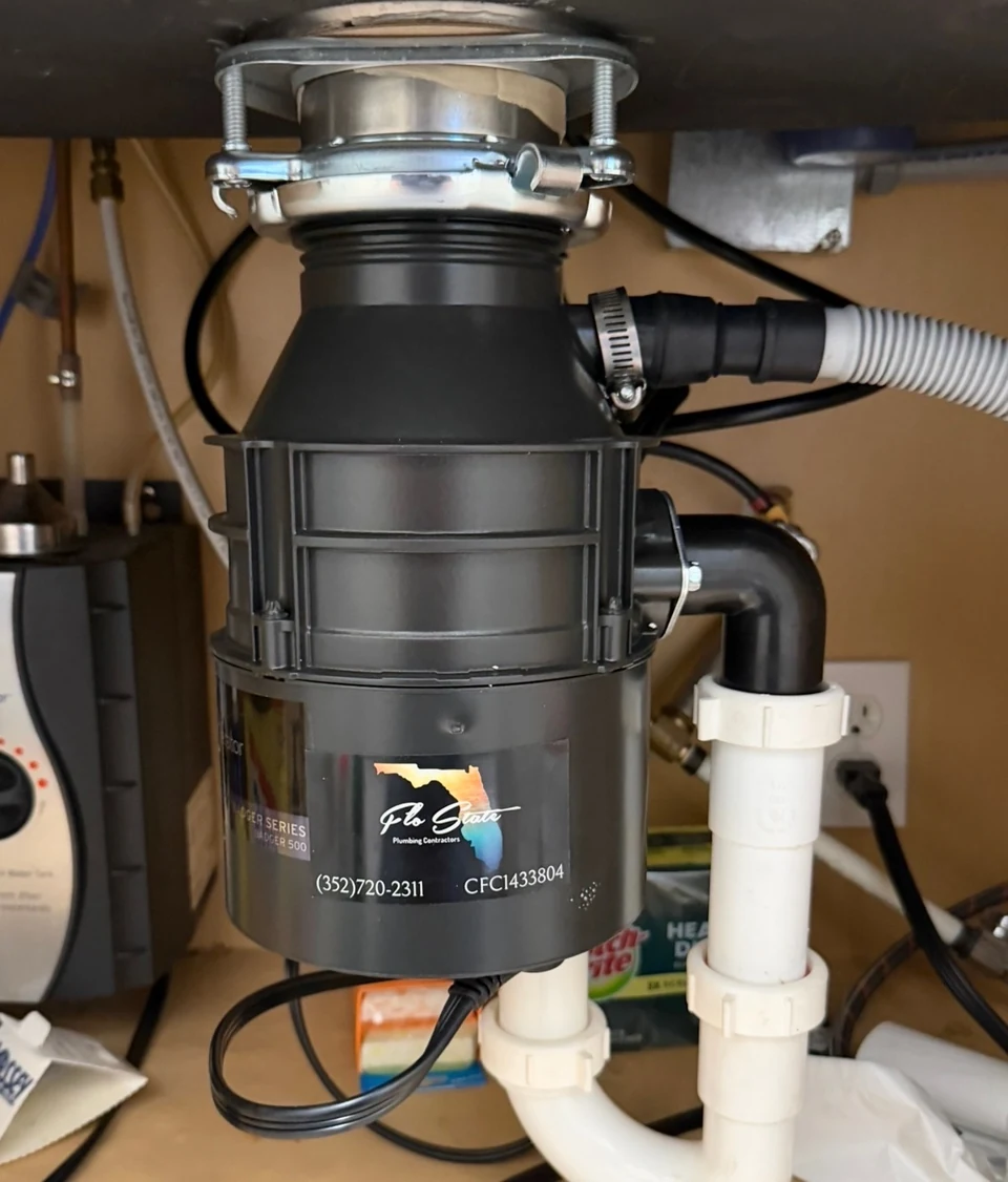 A garbage disposal connected to the kitchen sink drain and dishwasher hose.