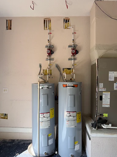 Two new electric water heaters installed side by side in a Central Florida garage
