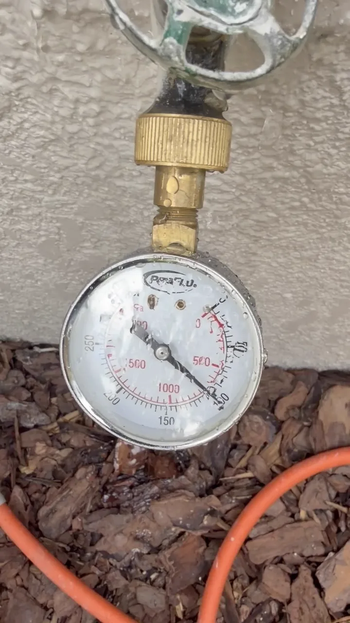 Pressure gauge on a hose bib reading 100 psi during a water pressure test
