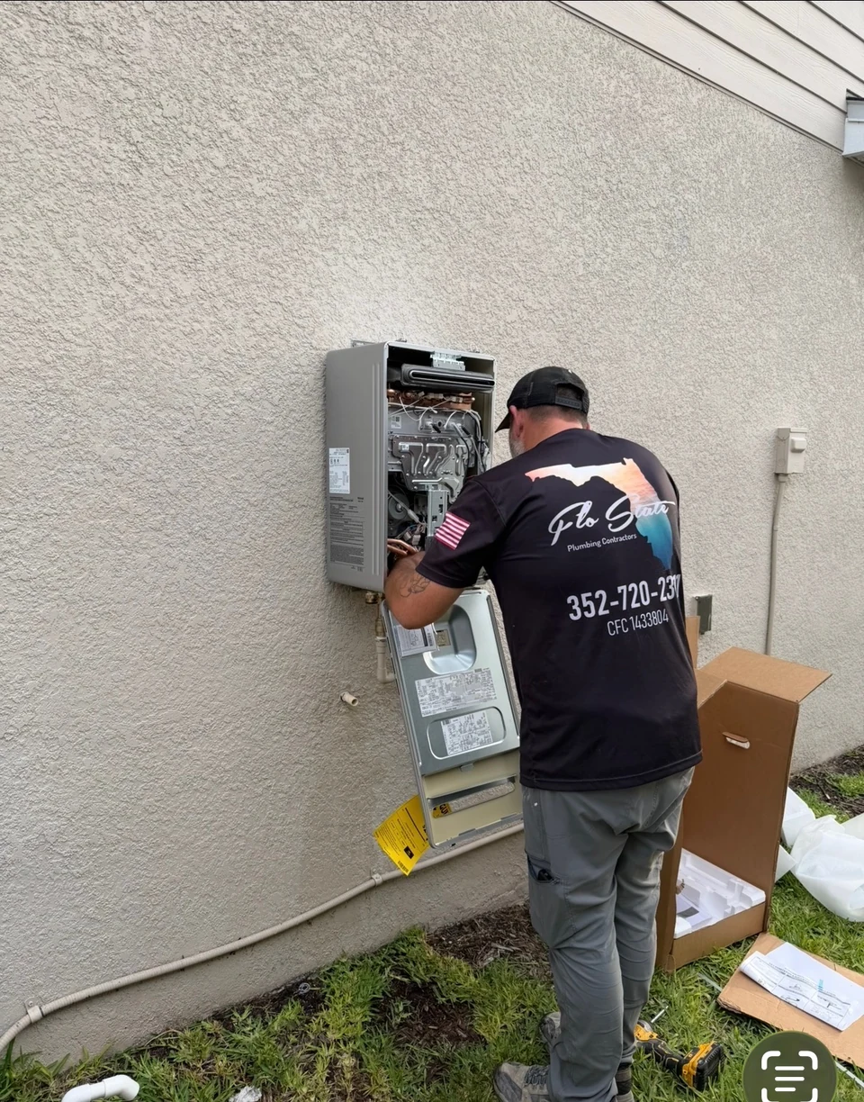 A Flo State technician working on a wall-mounted tankless water heater with its cover removed.